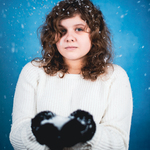 ZIMA. Dziewczyna w rękawiczkach trzyma kulę śnieżną.